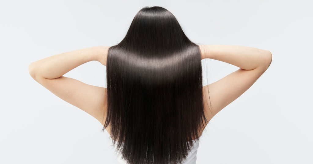 Woman with long, glossy black hair shown from behind, showcasing healthy and freshly dyed black hair